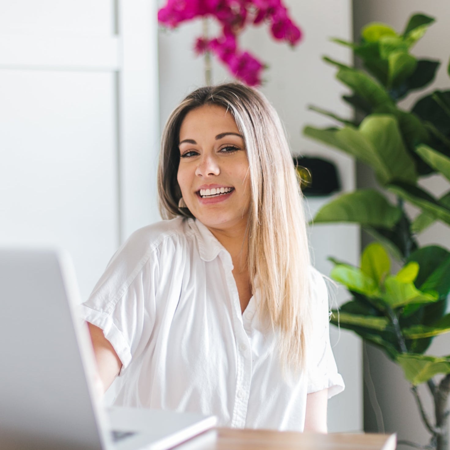 Woman smiling at camera while sitting behind computer